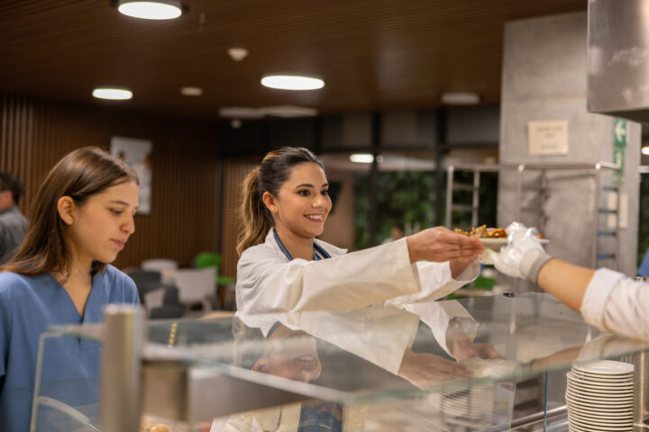 Glad läkare som tar emot sin talrik med mat i sjukhusets cafeteria