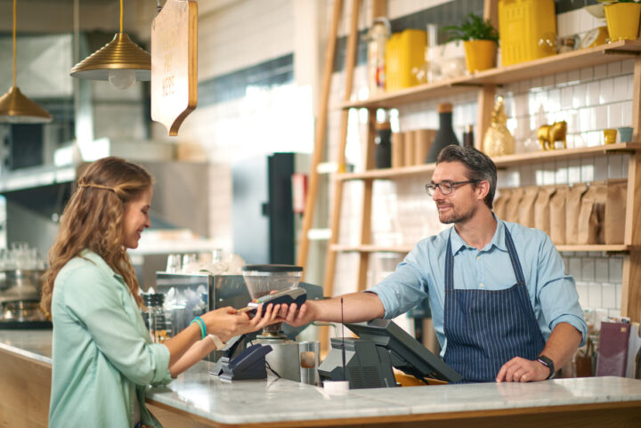 Woman paying for coffee with credit card at cafe